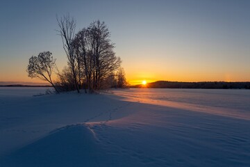 winter landscape in Karelia, lake under snow at sunset - obrazy, fototapety, plakaty