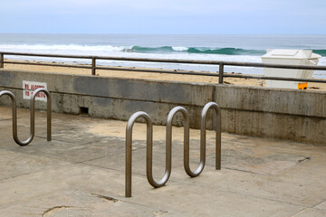 Public stainless steel wave shaped bike racks waiting for visitors near Pacific beach in early morning hours, San Diego, California