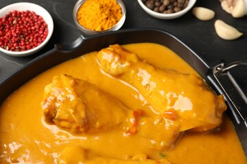Tasty chicken curry and ingredients on black table, closeup
