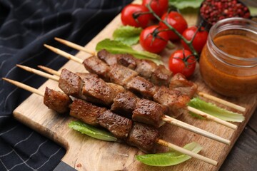 Tasty cooked marinated meat served with sauce and tomatoes on table, closeup