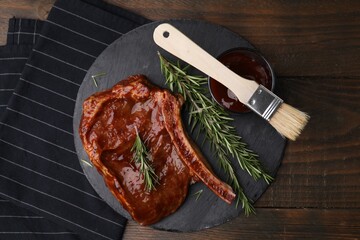 Tasty meat, rosemary, marinade and basting brush on wooden table, top view