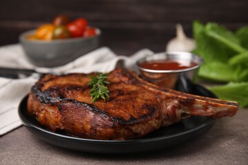Tasty grilled meat, rosemary and marinade on brown textured table, closeup - obrazy, fototapety, plakaty