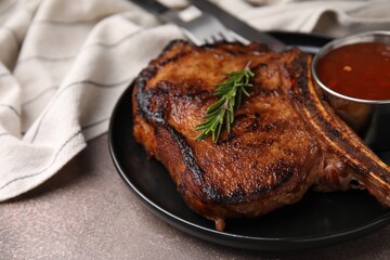 Tasty grilled meat, rosemary and marinade on brown textured table, closeup