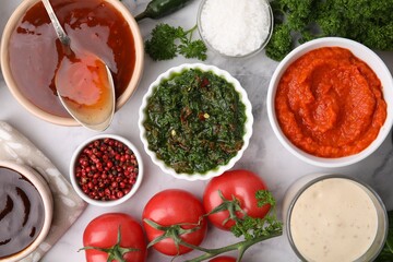 Different marinades and products on white marble table, flat lay