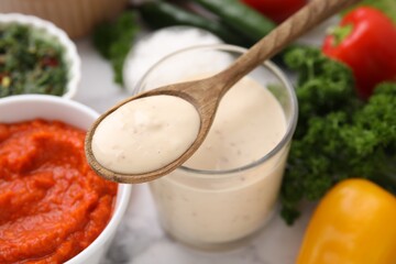 Spoon with fresh marinade over table, closeup