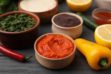 Fresh marinades in bowls and ingredients on grey wooden table, closeup