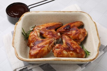 Fresh marinade, chicken wings and rosemary on white tiled table, closeup