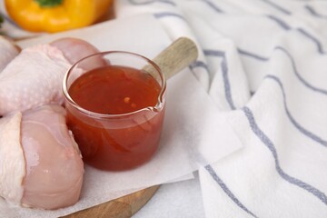 Fresh marinade and raw chicken drumsticks on table, closeup. Space for text