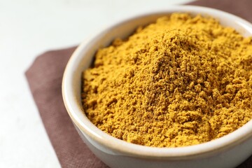 Curry powder in bowl on white table, closeup