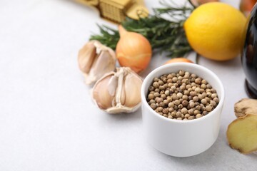 Aromatic peppercorns and different fresh ingredients for marinade on light grey table. Space for text