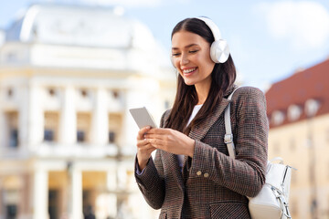Smiling woman using phone with headphones, copy space