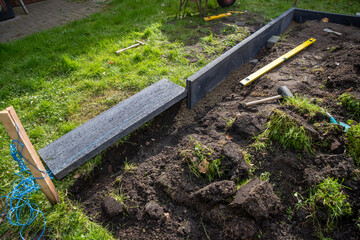 Bordsteine auf einer Baustelle im Garten mit Hammer und Wasserwage