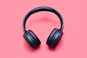 Black wireless headphones isolated on a red background. On-ear wireless headphones for playing...