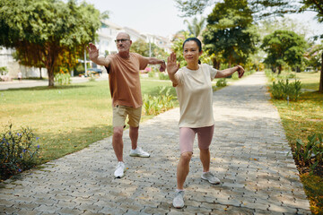 Diverse couple doing tai chi exercises in park