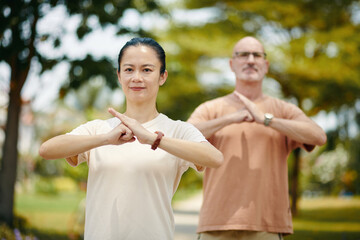 Smiling man and woman doing fist palm salute when practicing tai chi
