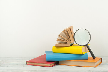 Open book, hardback colorful books on wooden table. Magnifier. Back to school. Copy space for text....