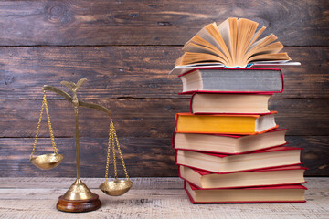 Law concept - Open law book, scales on table in a courtroom or law enforcement office.