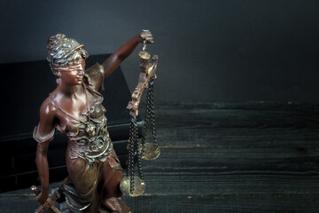 Themis and books on jurisprudence on a wooden background. Legal and law concept.