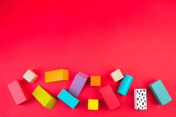 Top view of colorful wooden bricks on the table. Early learning. Educational toys on a red background.