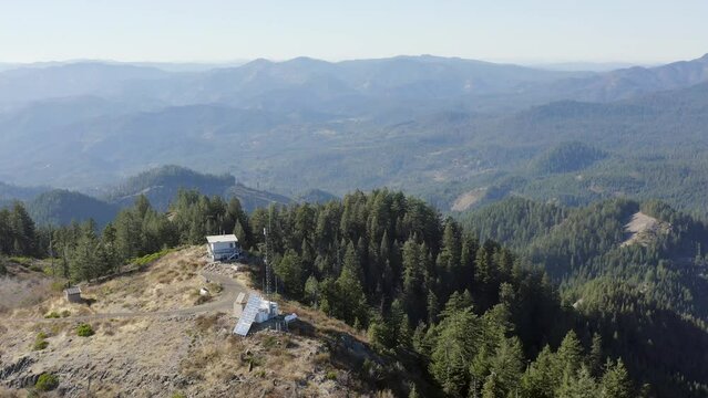 A mountain top with a cabin and a tower. The view is very beautiful and peaceful