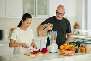 Mature couple making healthy smoothie for breakfast - 786574930