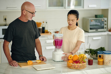 Diverse couple making dragon fruit smoothie for breakfast