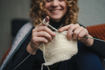 Close up of unrecognizable youngwoman knitting scarf at home. Girl knit. Knitting clothes, woman...