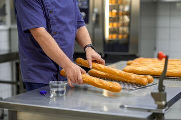 Unrecognizable man baker baking French baguette bread