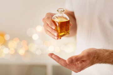 Hand holding bottle of massage oil with bokeh