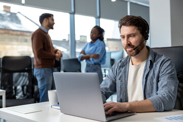 Attractive man in headset working on laptop