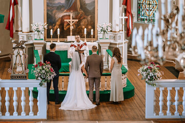 Valmiera, Latvia- July 28, 2024 - A wedding ceremony in a church with a priest, a couple at the...