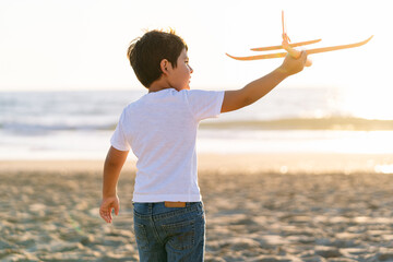 A boy holding a toy airplane looks out to the sea.