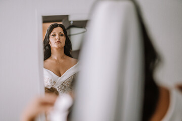 Valmiera, Latvia- July 28, 2024 - A bride in an off-shoulder wedding gown is reflected in a mirror...