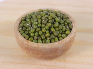 Green raw mung beans in wooden bowl on wooden and white background