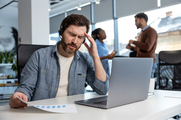 Exhausted man call center operator suffering headache at workplace