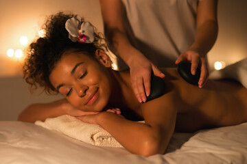 Relaxing hot stone massage therapy session for black lady