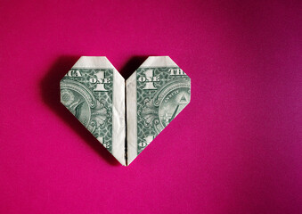 Dollar bill origami heart shape on pink textured background - 786593321