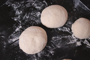 Overhead view of round pizza doughs on top of a black granite table.