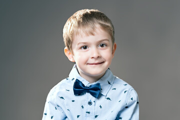 Portrait of little boy with brown eyes in blue shirt and bowtie looking straight into the camera...