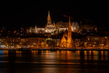 Obraz premium Night photo of Budapest city waterfront with Castle Hill and famous landmarks such as Fisherman`s bastion and Mattias Church rising above Danube river