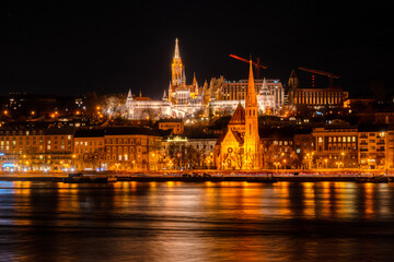 Night photo of Budapest city waterfront with Castle Hill and famous landmarks such as Fisherman`s bastion and Mattias Church rising above Danube river