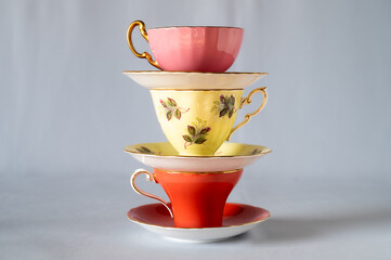 Three tea cups and saucers  in a stack on light grey background
