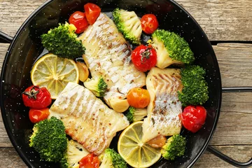 Poster Tasty cod cooked with vegetables in frying pan on wooden table, top view © New Africa