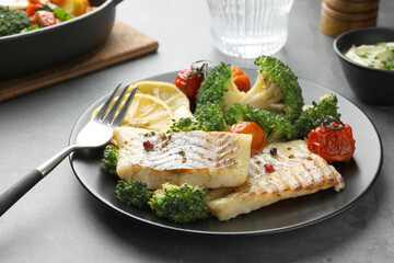 Tasty cod cooked with vegetables served on grey table