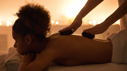 Woman receiving hot stone massage at spa