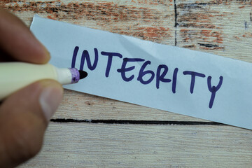 Concept of Integrity write on sticky notes isolated on Wooden Table.