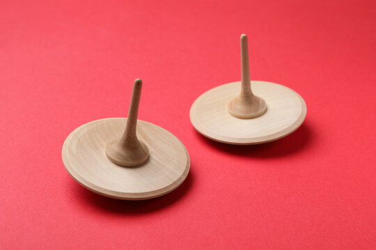 Two wooden spinning tops on red background, closeup