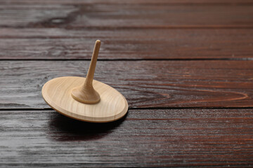 One spinning top on wooden table, closeup. Space for text