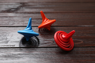 Bright spinning tops on wooden table, closeup