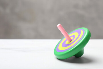 One bright spinning top on white table, closeup. Space for text